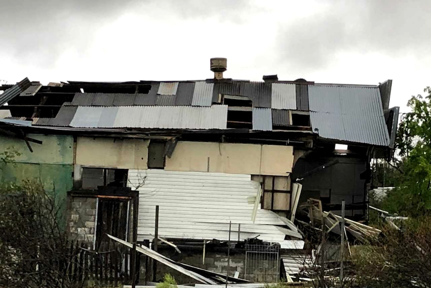 A badly damaged building, missing parts of its tin roof and wall, after being hit by a hailstorm