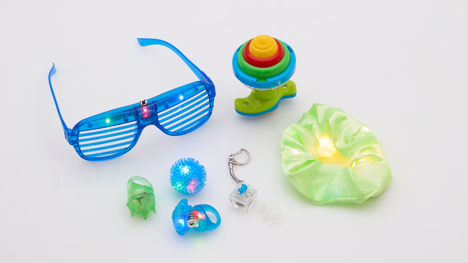 Um par de óculos de fita, anéis de gelatina, um elástico de cetim, um Spin top com lançador e um chaveiro com botão de teclado. 