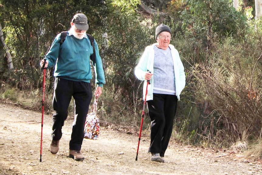 Man and woman bushwalking along dirt track