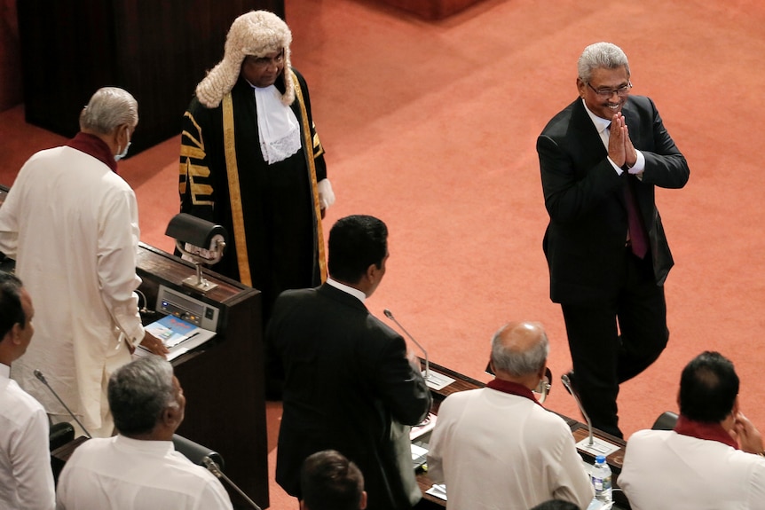 The president speaker of the house walk past MPs in parliament.