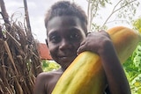 A young boy with a giant pawpaw.