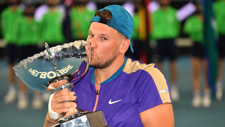 Dylan Alcott kisses the Australian Open while looking at camera.