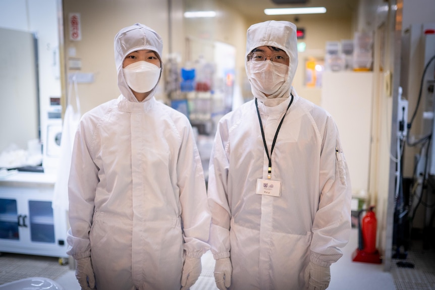 실험실에서 흰색 PPE와 안면 마스크를 착용한 두 한국인 
