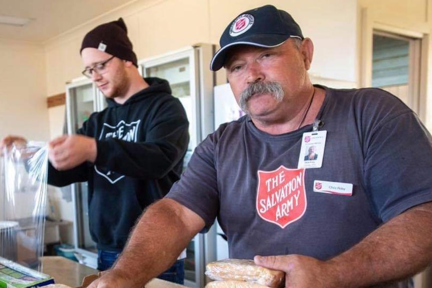 A man preparing sandwiches looks to the camera.