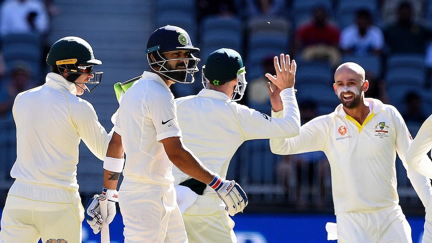 Virat Kohli walks off as Nathan Lyon high fives a teammate in the background