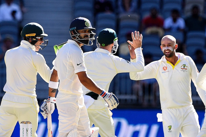 Virat Kohli walks off as Nathan Lyon high fives a teammate in the background