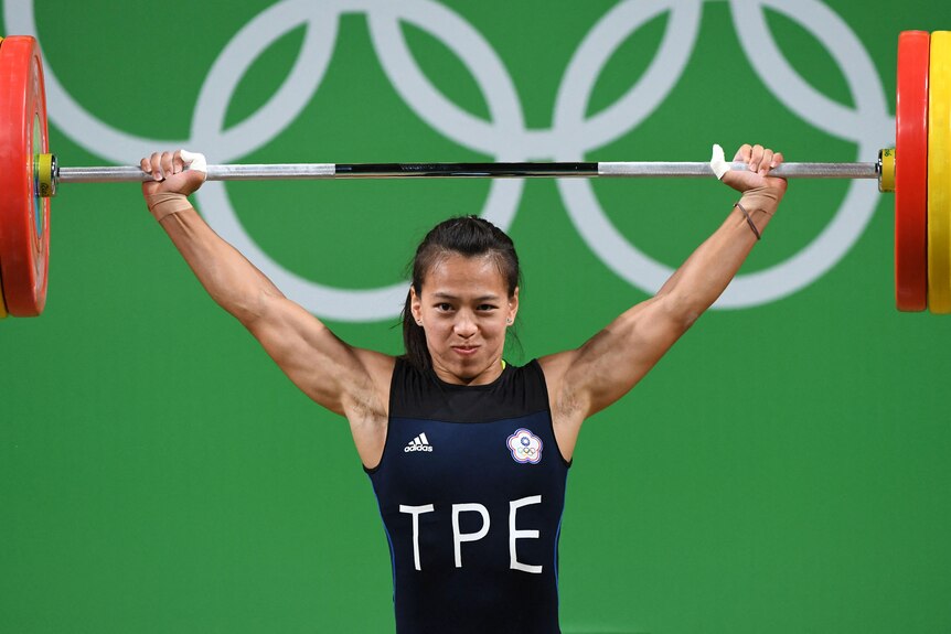 A woman lifts weights at an Olympic event wearing a uniform for Chinese Taipei.