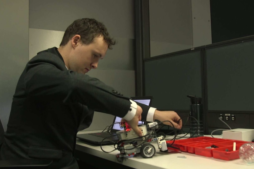 Sam Castleman works with a robot during the trial program