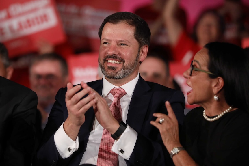 Ed Husic and Linda Burney smile and clap, surrounded by Labor supporters