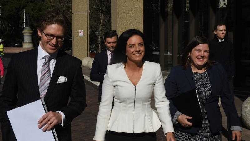 A man and two women walk side by side along a street.