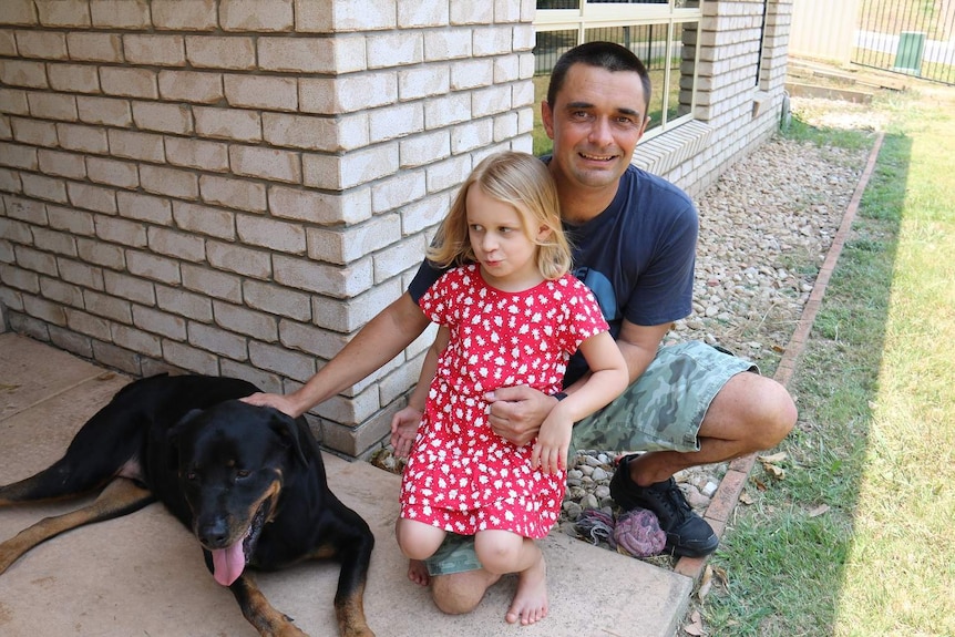 Griffin lays on ground with owner Adam Johnson and daughter Layla.