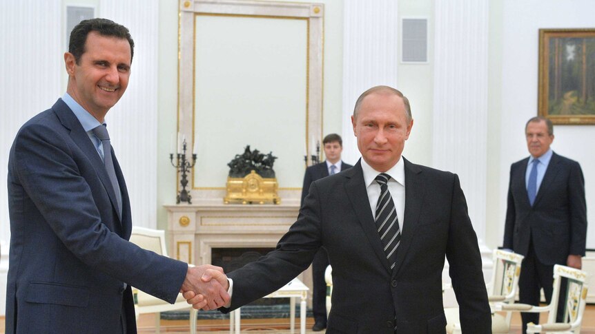 Vladimir Putin shakes hands with Bashar al-Assad