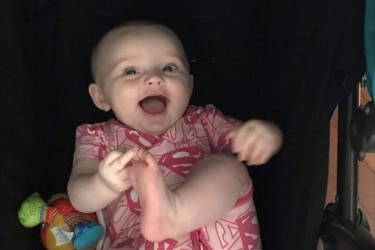 Baby Chloe Conley touching her toes and smiling.