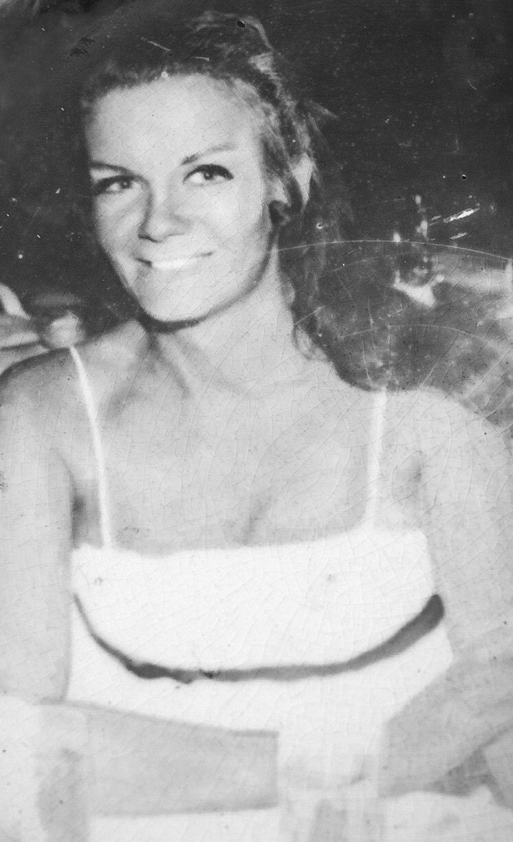 A glamourous woman who is also a jewel thief from the 1960s smiles for the camera.