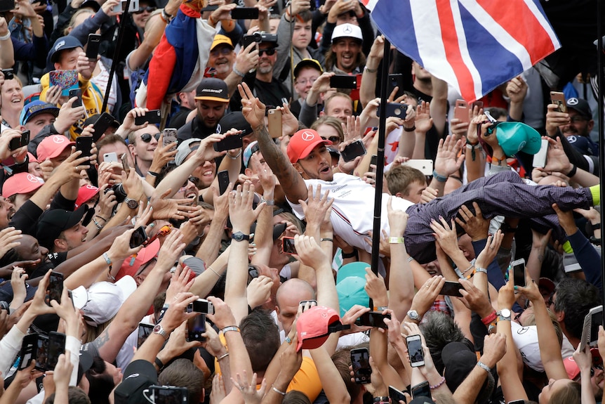 Lewis Hamilton is hoisted up by celebrating fans after winning the British GP at Silverstone
