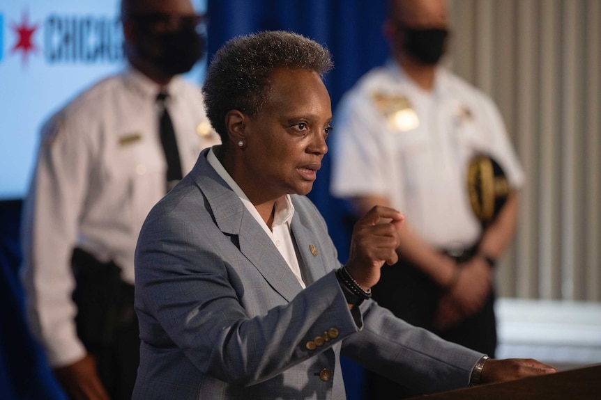 Chicago Mayor Lori Lightfoot gestures with her right hand while speaking at a lectern.