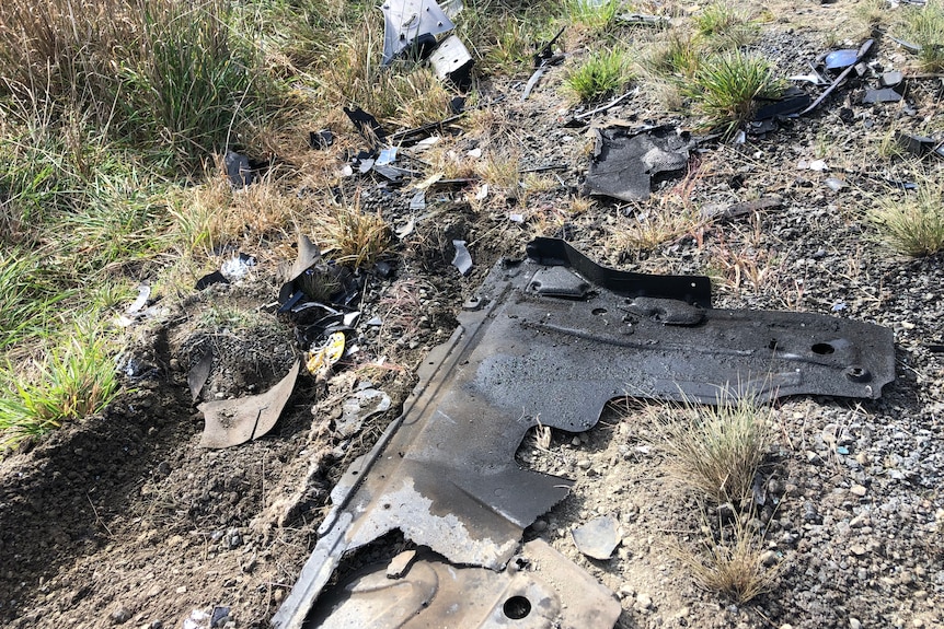 Oil-covered metal debris on the side of a road.