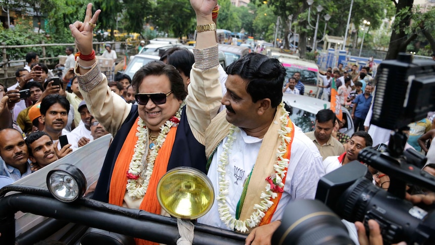 Bappi Lahiri stands in a vehicle and campaigns for a political candidate