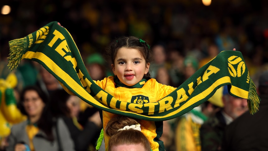 A young football fan holding an Australia scarf