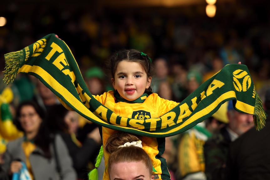 A young football fan holding an Australia scarf