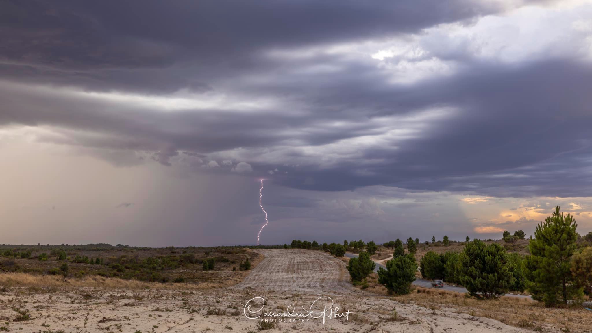 A lightning bolt and purple grey skies, over sparse bushland in WA