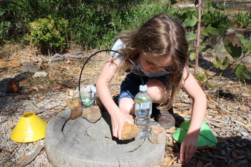 A girl conducts an experiment using water bottles outside.