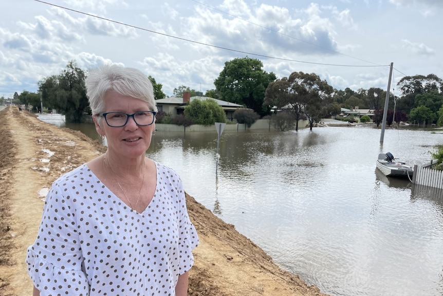 A woman on a levee in front of a flooded street