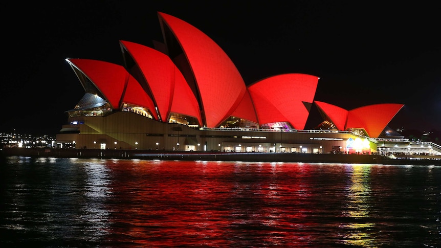 The Opera House is seen in deep red light.