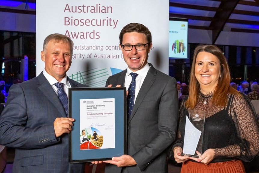 Shane Templeton holds a framed award beside David Littleproud and Julie Templeton.