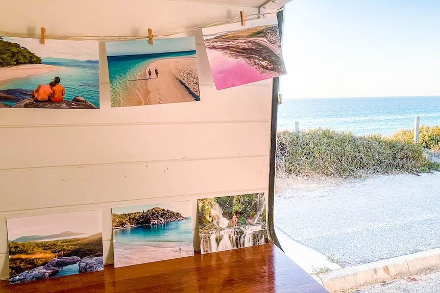 Holiday photos hanging on the side of a van looking out at a beach.