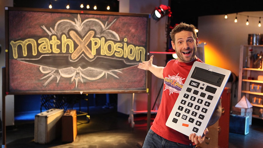Smiling man holds large calculator in front of blackboard with text "MathXplosion"