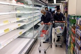 Customers wearing masks shop in front of partially empty shelves at a supermarket in Hong Kong. 