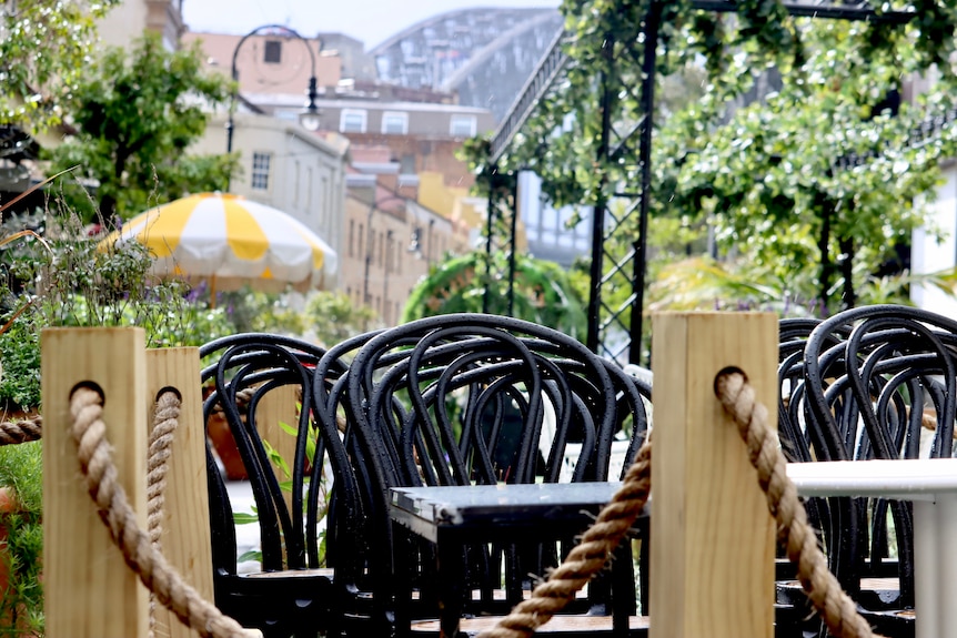 Chairs stacked up outside a restaurant, Sydney Harbour Bridge in the background