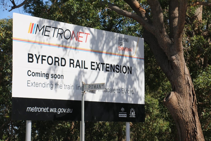 A sign advertising Metronet with trees in the background.
