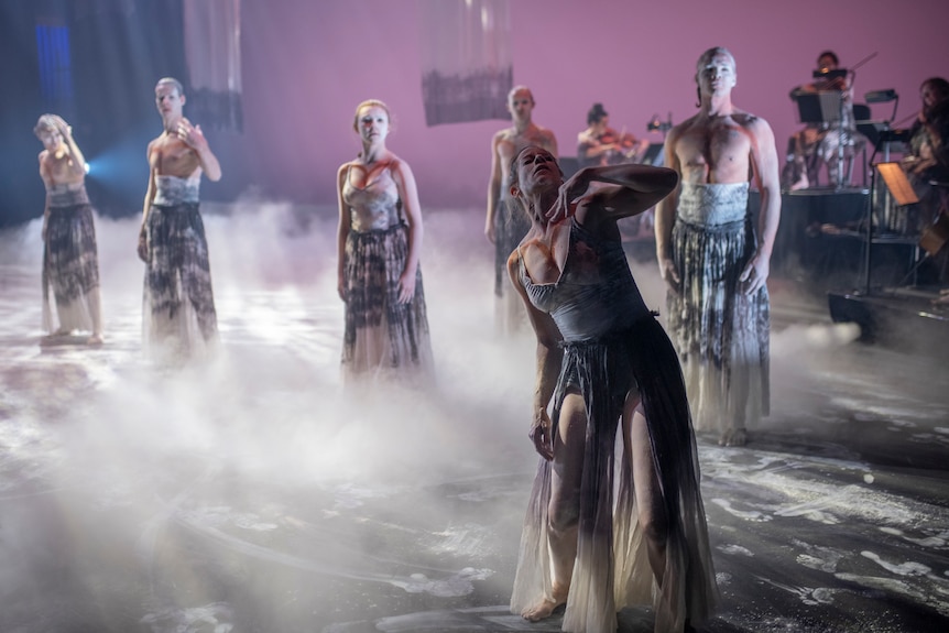 A group of dancers surrounded by smoke on stage.
