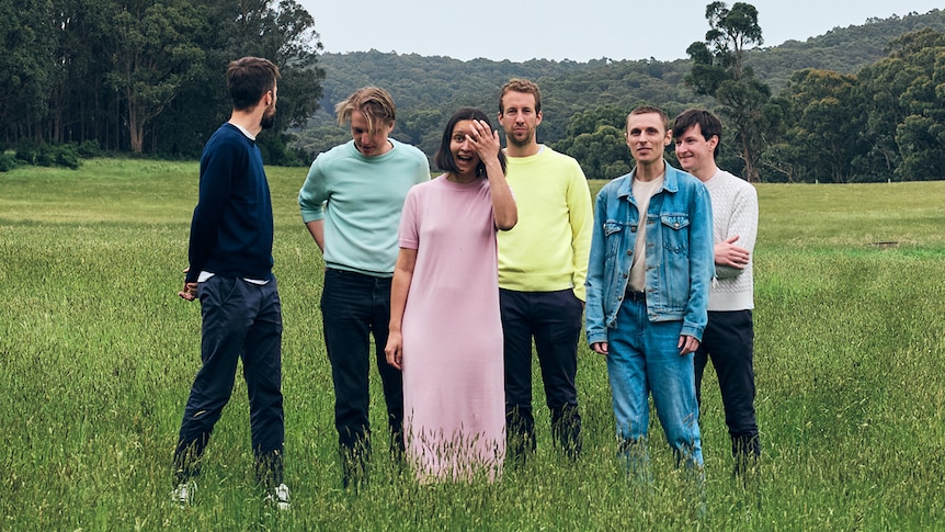 Six members of Cool Sounds standing in a green field wearing pastel colours