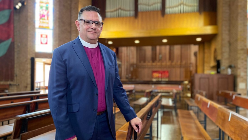 Anglican Diocese of Bathurst Bishop Mark Calder leans against pew inside church