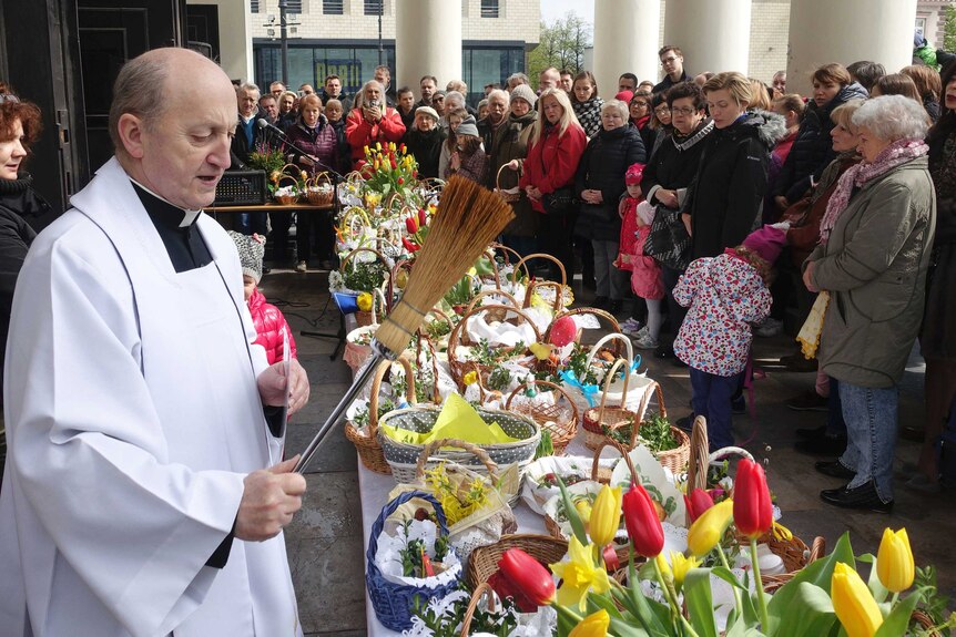 A priest blesses baskets of food samples in front of a church in front of a church in Warsaw ahead of Easter Sunday.