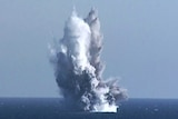 An underwater blast lifts water high above the ocean's surface.