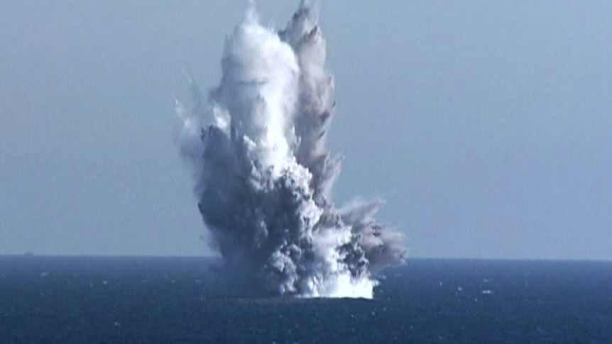 An underwater blast lifts water high above the ocean's surface.