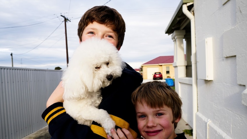 Shylie's two young boys hold their dog 'Novo' in the family driveway.