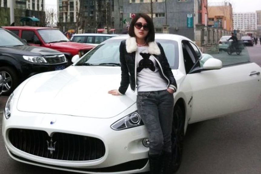Chinese woman Guo Meimei stands in front of a white luxury car.