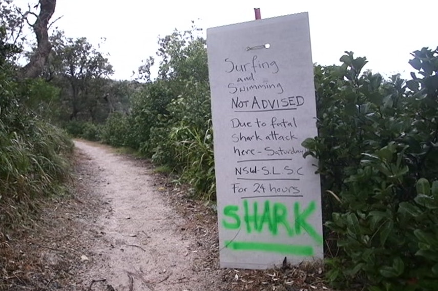 A sign on a beach path hat says surfing and swimming not advised.