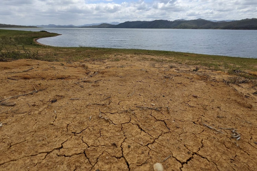 View over dry earth and a low level of water in a dam