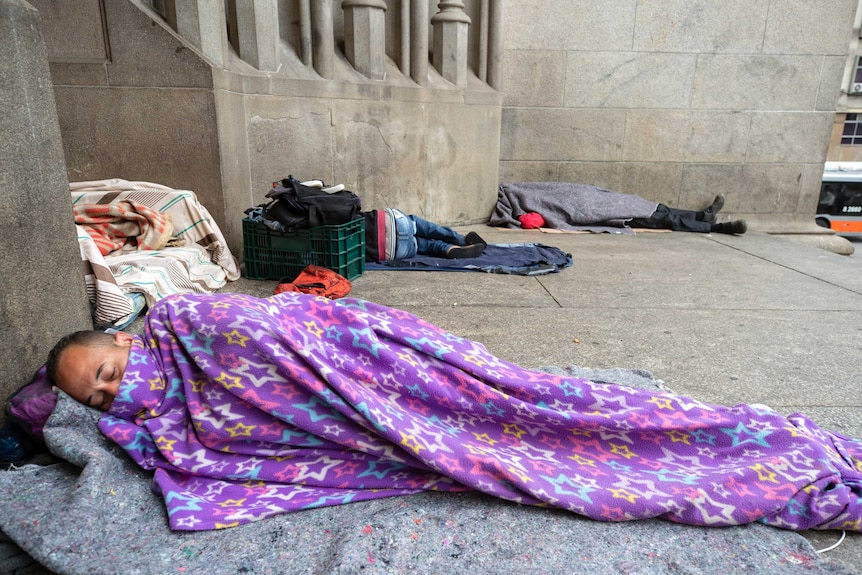 Homeless people sleep in sleeping bags against the exterior walls of a Cathedral in Sao Paulo.