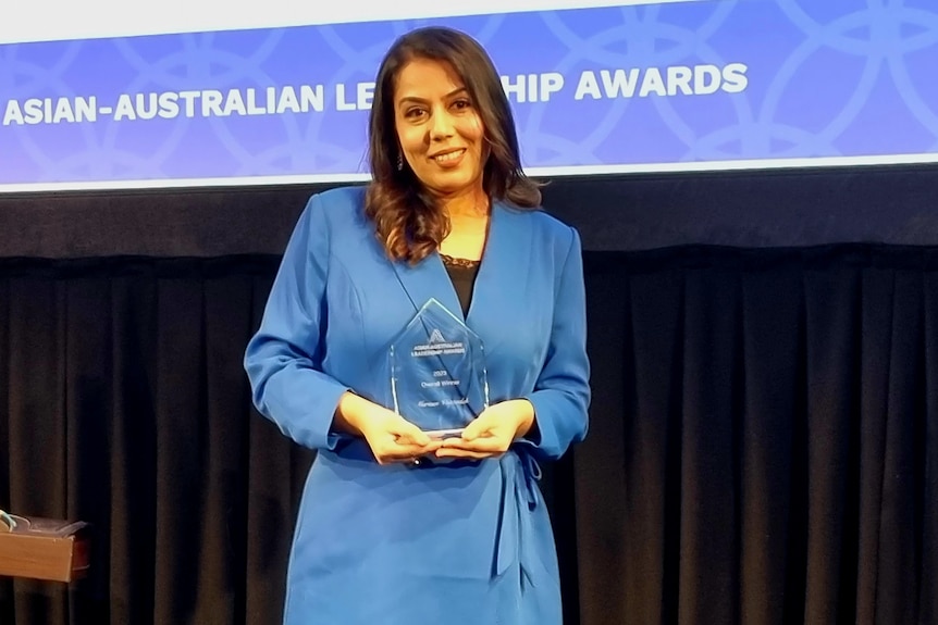 woman wearing blue holding a glass award