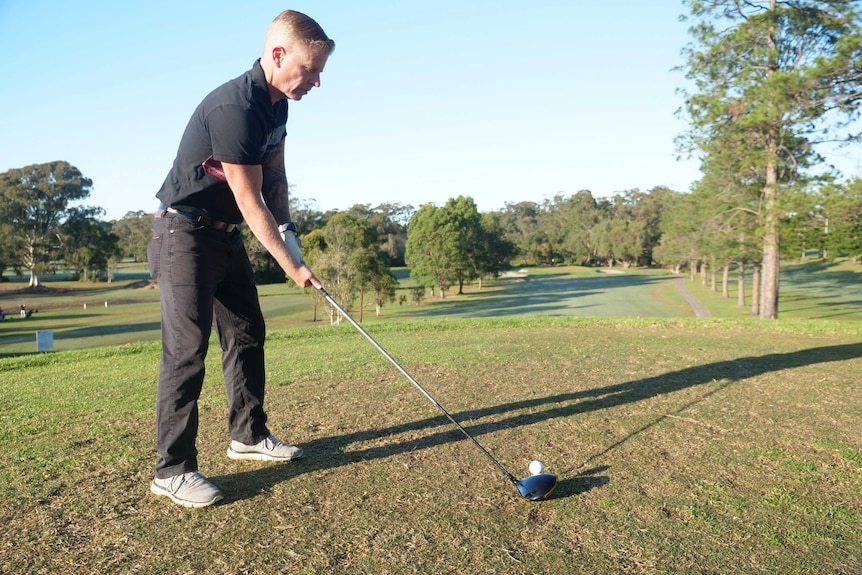 A golfer is about to take a swing at the ball.