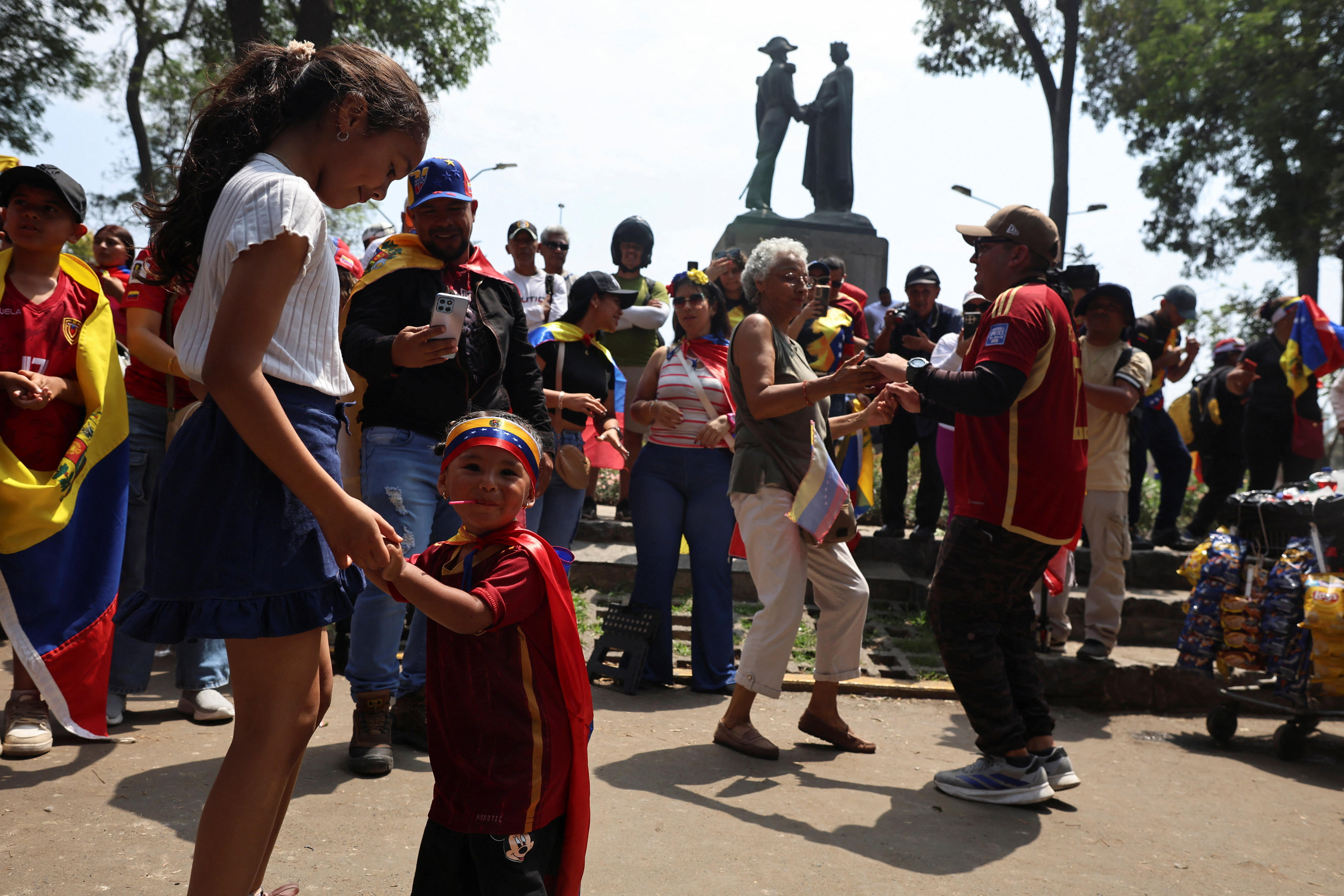 Mujeres y niños se dan la mano y bailan.