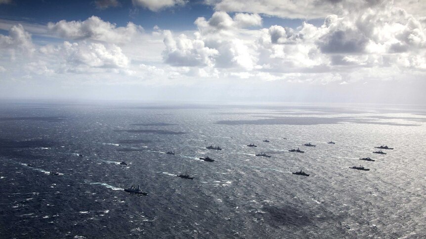 A multi-national fleet of ships sail in formation off the coast of Jervis Bay.