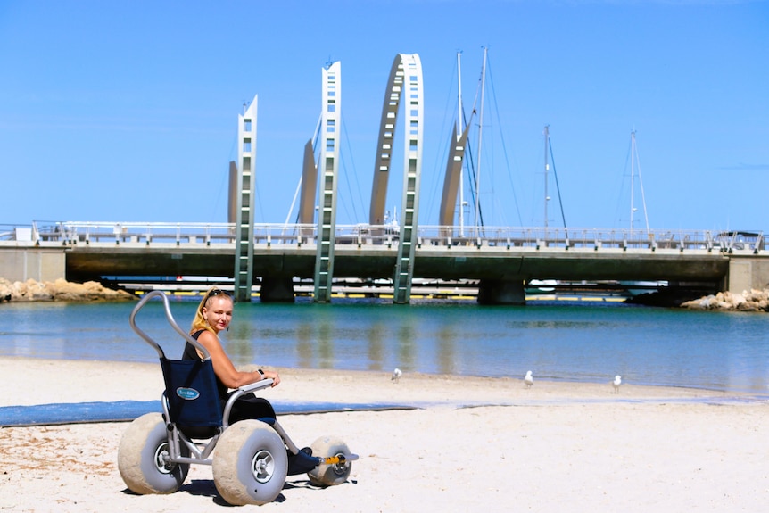 She sits in a beach wheelchair on a beach